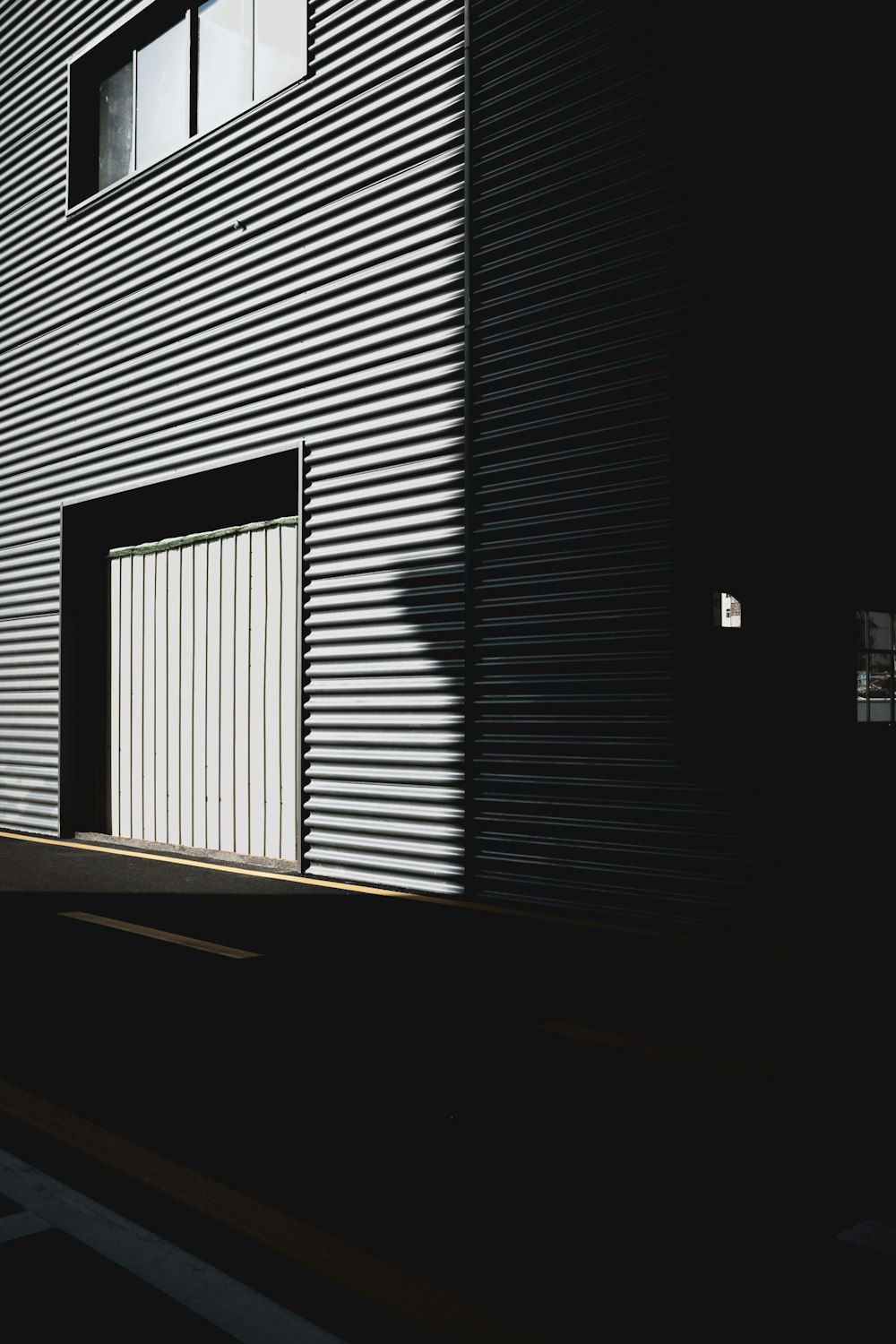 Corrugated warehouse wall and door in hard light and shadow