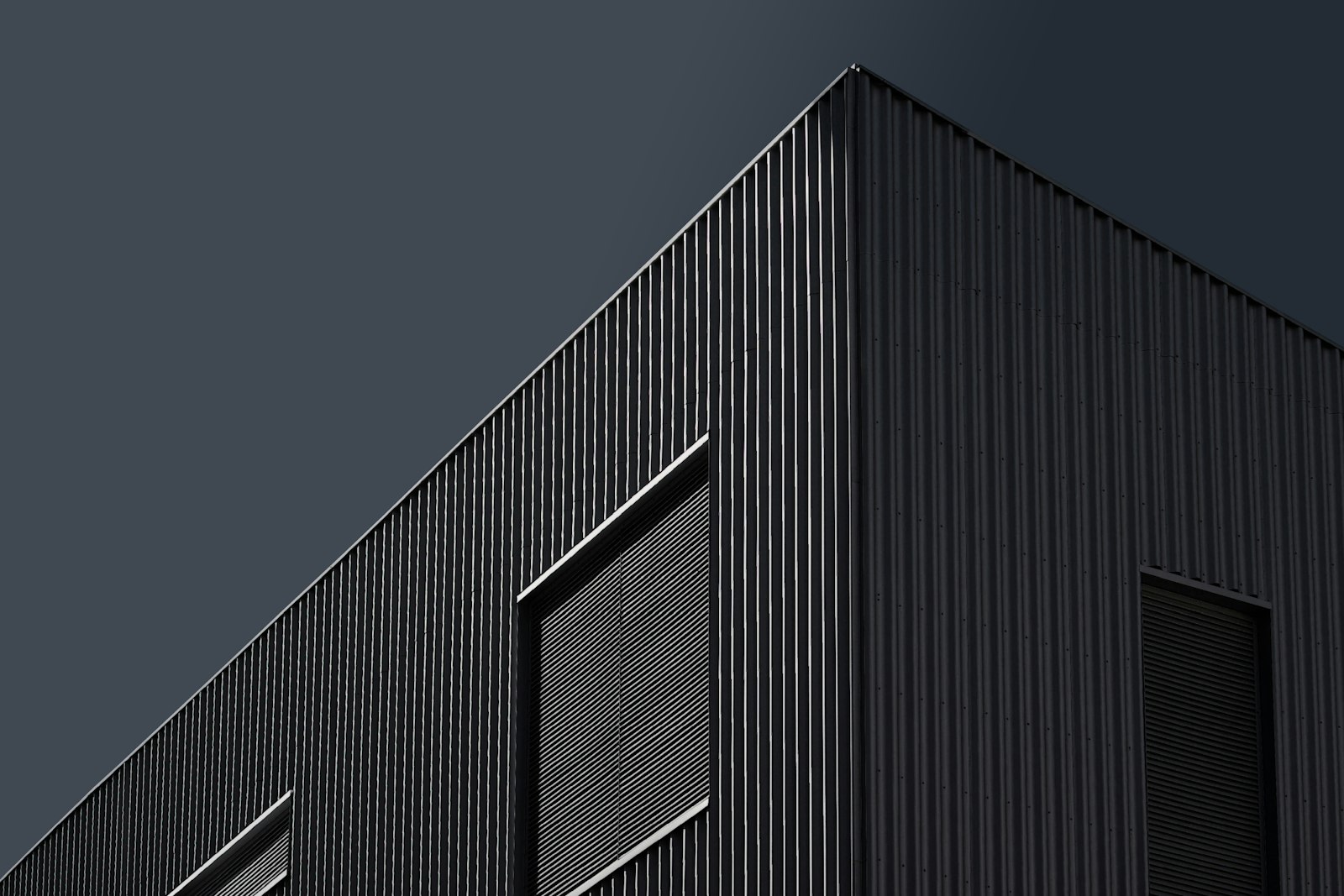 Dark corrugated warehouse with a loading door, under an evening sky