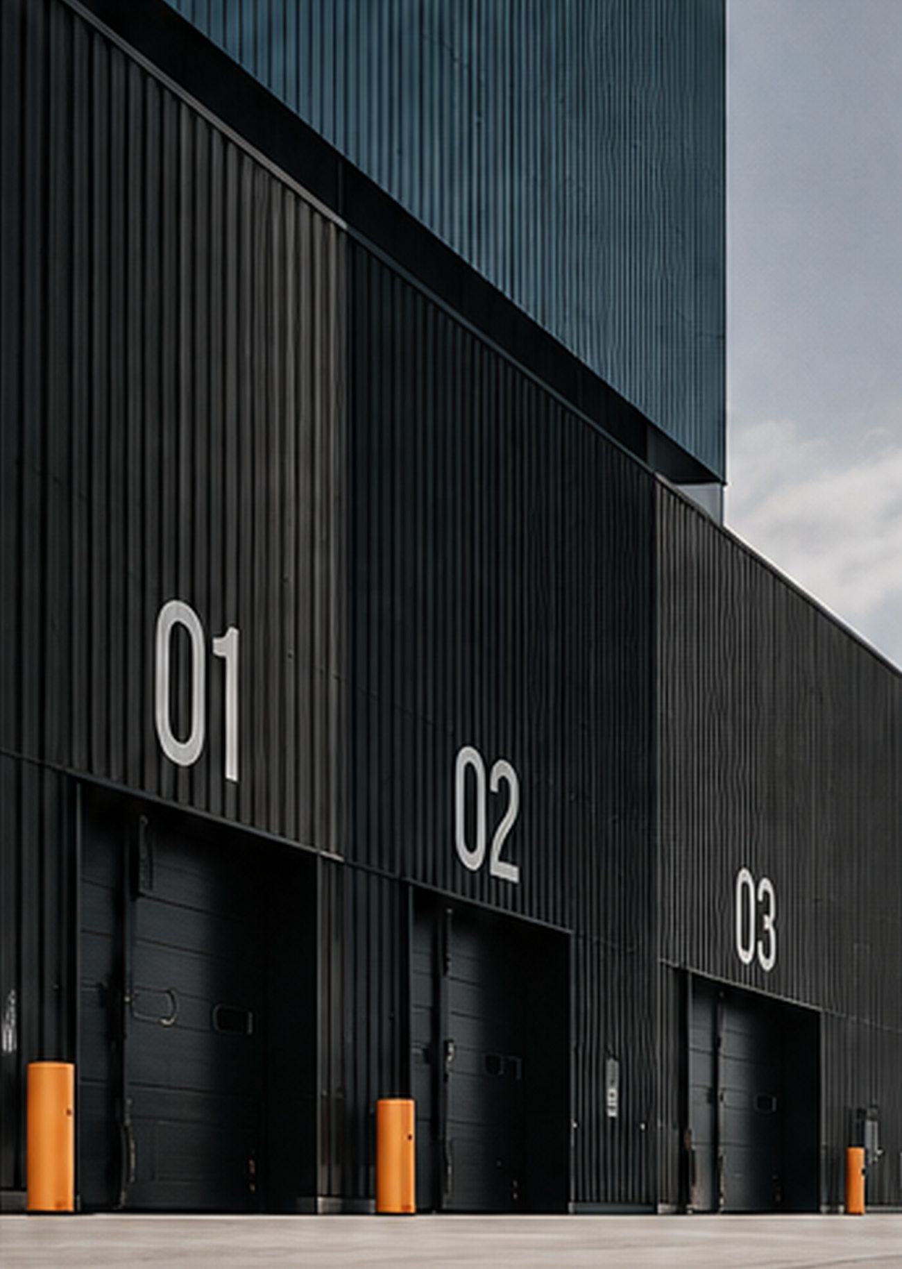 Black warehouse with numbered loading docks 01, 02 and 03 and orange bollards